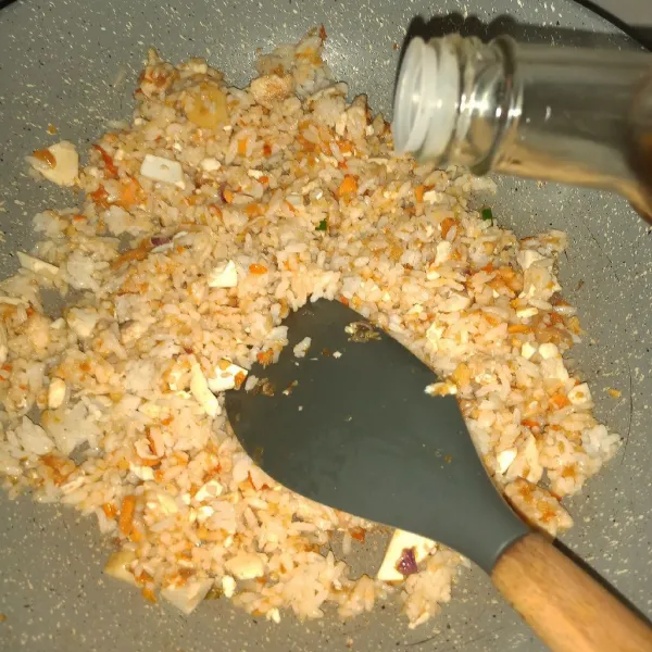 Masukkan nasi, aduk-aduk. Tuang kecap ikan, aduk dan masak sampai cukup matang. Tes rasa sebelum menambahkan kaldu bubuk dan garam.