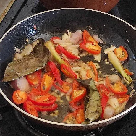 Tumis hingga harum irisan bawang merah, bawang putih, irisan cabai merah, serai geprek, daun salam, garam, dan kaldu bubuk