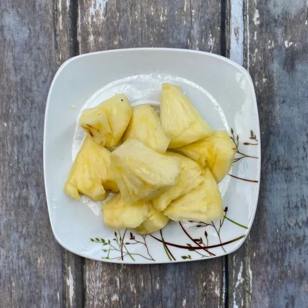 Kupas dan potong-potong nanas.