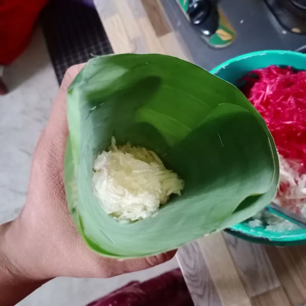 Cetak singkong putih sambil ditekan-tekan pada daun pisang yang sudah dibentuk kerucut .