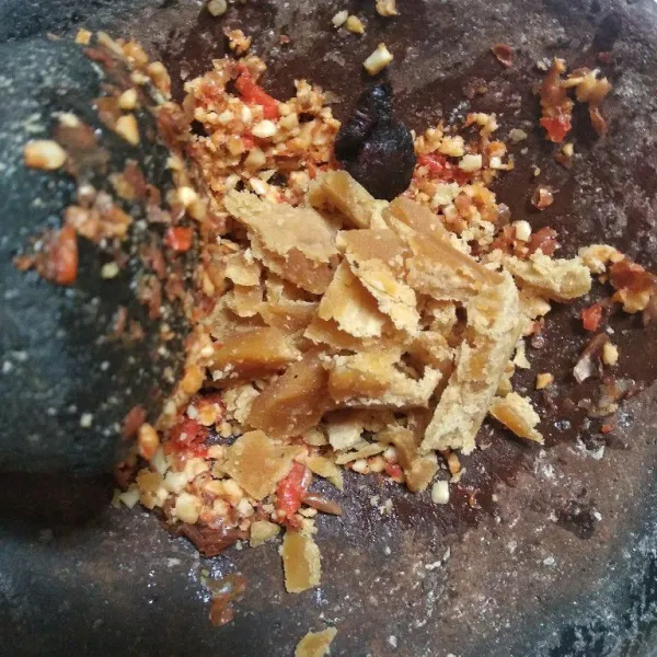 Masukkan gula merah dan asam Jawa. Ulek kembali. Beri satu potong timun supaya bumbu tidak terlalu kental.