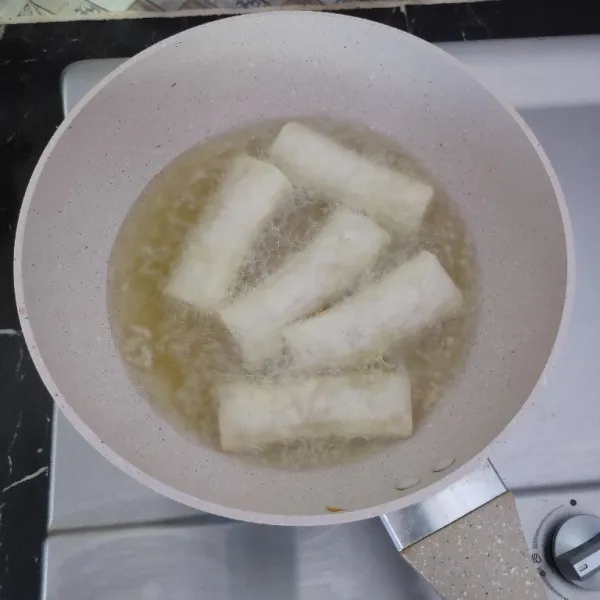 Goreng lumpia dalam minyak panas api sedang hingga matang kecoklatan.
