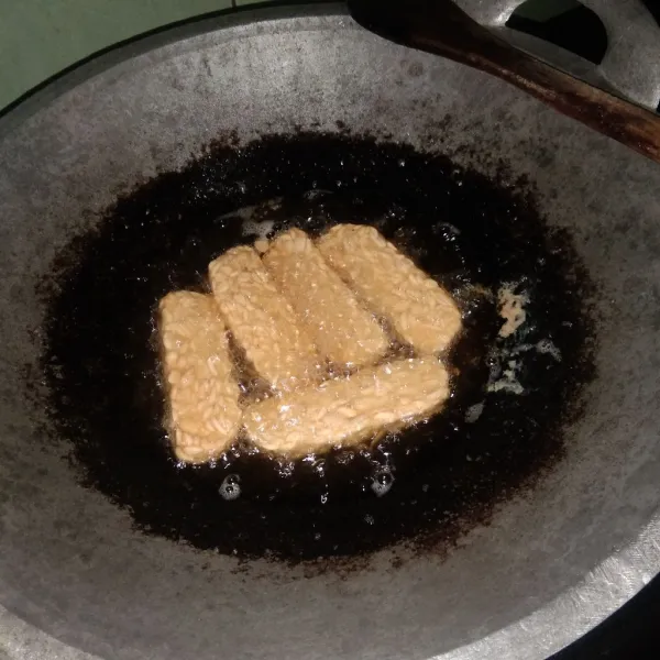 Goreng tempe yang sudah dipotong hingga matang tapi tidak sampai kering.