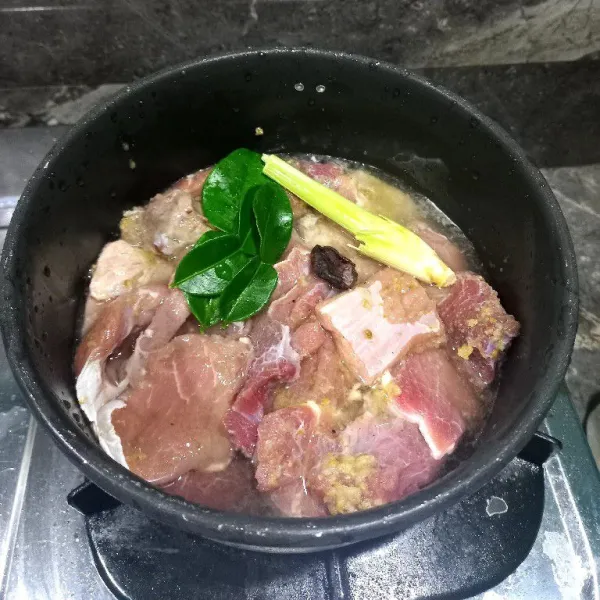 Siapkan panci, lalu rebus daging sapi. Masukkan bumbu halus, garam, daun jeruk, salam, dan asam kandis. Rebus hingga air rebusan tersisa sedikit