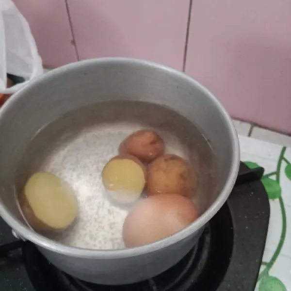 Belah kentang menjadi dua bagian kemudian rebus kentang dan telur hingga matang.