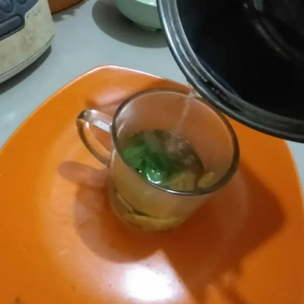 Rebus air ke dalam panci sampai mendidih kemudian tuangkan ke dalam gelas berisi jahe dan daun pandan.