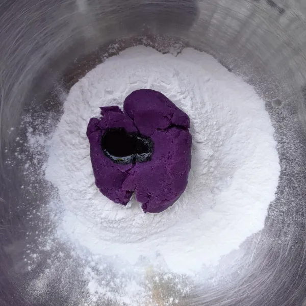 Siapkan wadah, masukkan tepung ketan, ubi ungu yang sudah dihaluskan dan pewarna makanan ungu. Aduk hingga menjadi adonan berpasir.