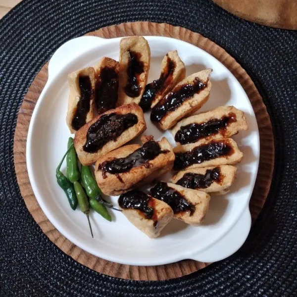Belah tidak putus bagian tengah tahu goreng, isi dengan sambal petis, sajikan.