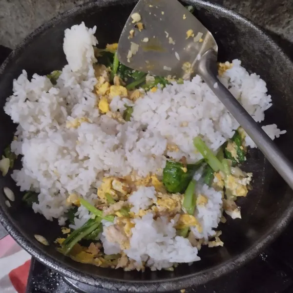 Masukkan sawi hijau, nasi putih, garam, lada dan kaldu bubuk.