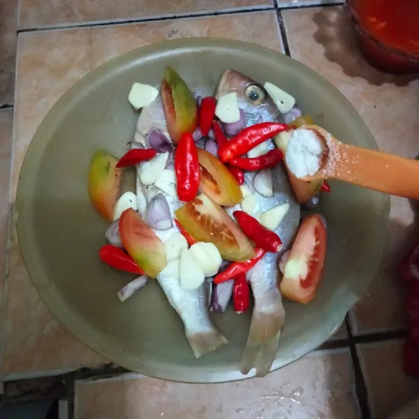 Ambil piring tahan panas untuk mengukus, beri 1/2 bagian bumbu iris di piring, tata ikan di piring, lalu beri semua sisa bumbu iris di atas ikan, beri sejumput garam.