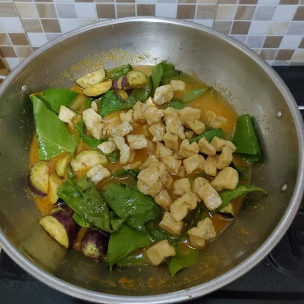 Tambahkan air, lalu masukan terong ungu, daun so dan tahu yang sudah digoreng aduk rata. Masak sampai mendidih dan terong matang.