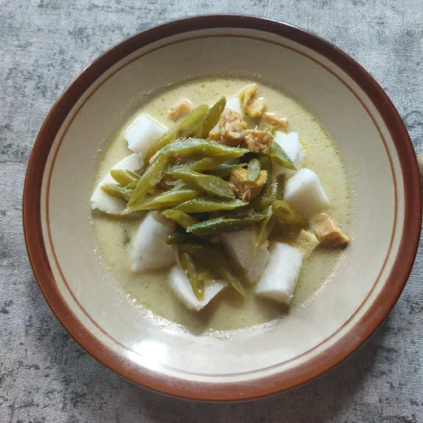 Siapkan piring saji, tata potongan lontong, lalu tuang kuah gulai dan isinya. Sajikan dengan kerupuk merah