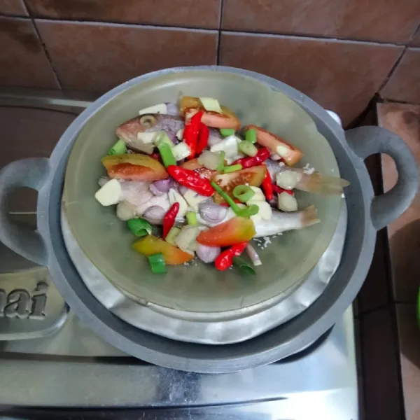 Panaskan kukusan berisi air sampai mendidih, masukkan piring berisi ikan.