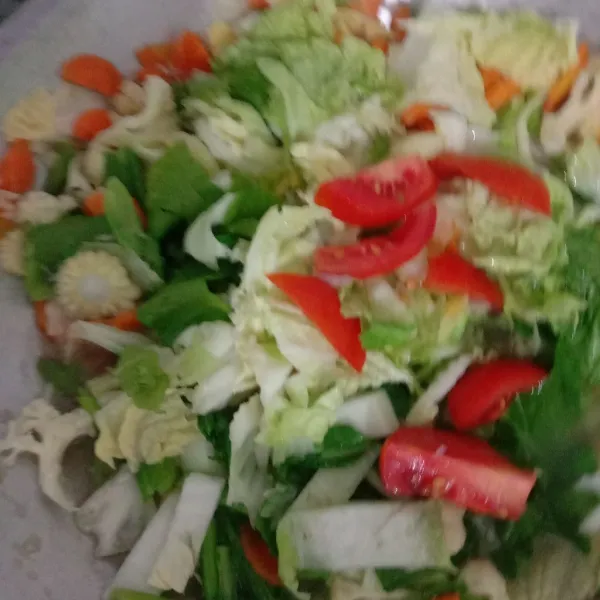 Buka tutup wajannya lalu tambahkan sawi hijau, sawi putih dan tomat merah, aduk sampai sayur layu.