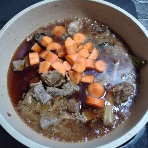 Masukkan daging dan wortel, tuang 250 ml air, tambahkan gula merah dan kecap manis, masak hingga mendidih.