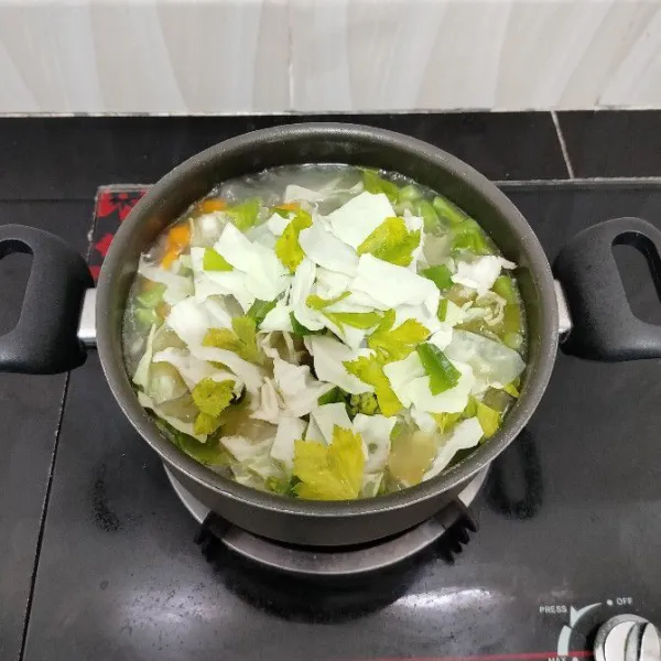 Lalu masukkan kubis, daun bawang prei, dan daun seledri. Aduk rata. Masak hingga matang.