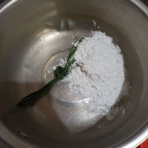 Masukkan tepung beras, santan bubuk, dan daun pandan ke panci