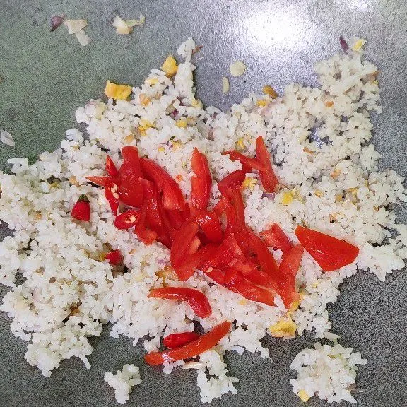 Masukkan tomat dan cabai pada setengah bagian nasi goreng yang tersisa. Aduk perlahan sembari koreksi rasa. Kemudian, sajikan bersama nasi goreng putih membentuk bendera merah putih dengan topping telur gulung iris