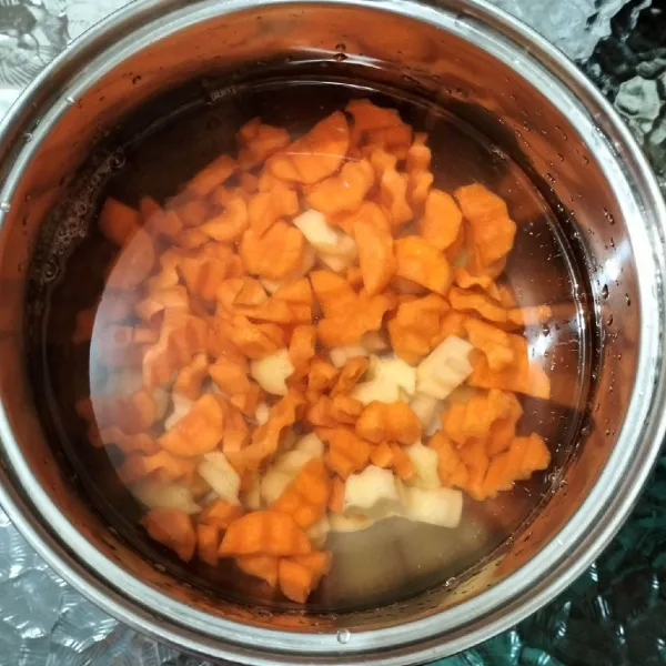 Didihkan air dalam panci. Lalu masukkan kentang dan wortel.