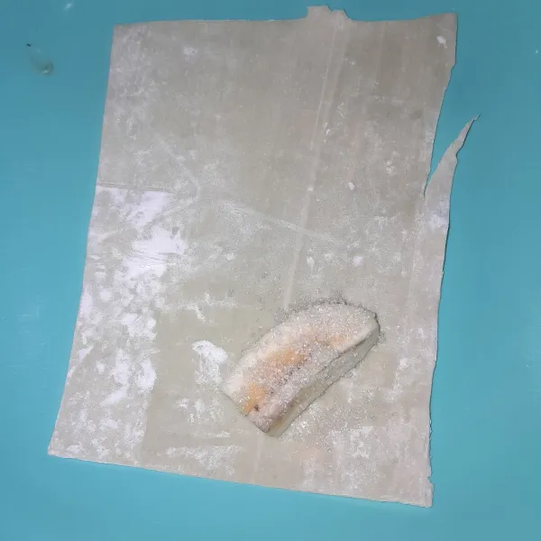 Ambil selembar kulit langsit, letakkan pisang dan beri gula pasir.