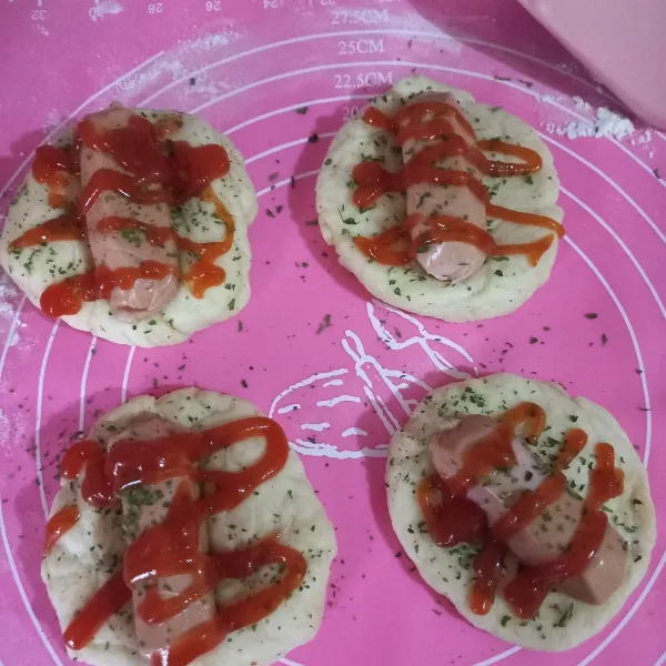 Pipihkan roti, tambahkan sosis di tengahnya sambil agak ditekan, beri saus dan taburan oregano secukupnya