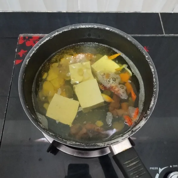 Kemudian masukkan tahu dan garam. Masak hingga mendidih.