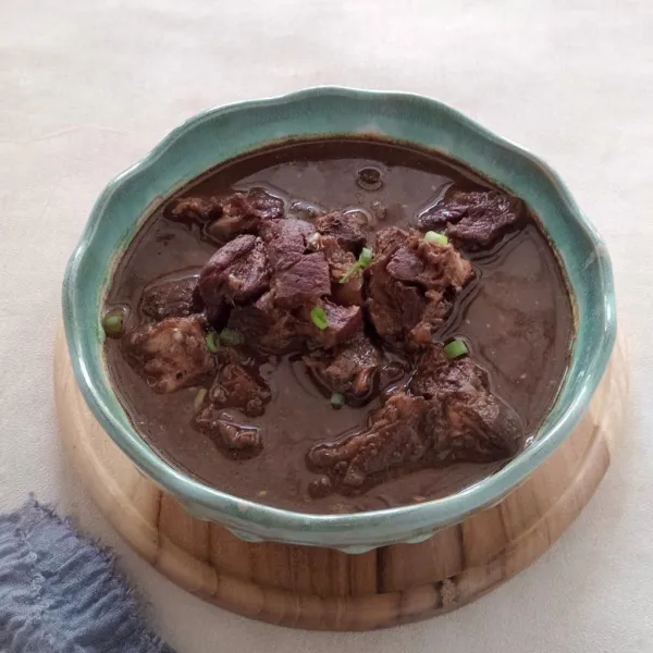 Sajikan rawon daging sapi dengan taburan daun bawang.