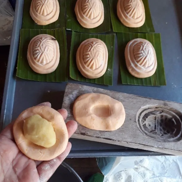 Panaskan kukusan. Pipihkan adonan, isi dengan pasta kacang hijau, bentuk bulat lonjong. Letakkan di atas cetakan kue tok, tekan-tekan. Keluarkan dari cetakan dan letakkan di atas daun pisang yang sudah diolesi minyak.