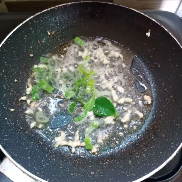 Tumis bawang putih sampai harum. Masukkan daun bawang dan daun jeruk, aduk rata.