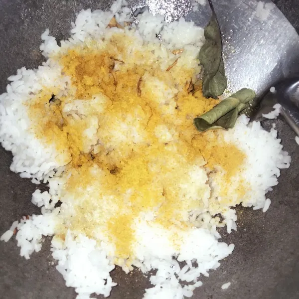 Masukkan nasi, kunyit bubuk, santan bubuk, kaldu bubuk, garam, gula pasir, daun jeruk, dan daun salam.