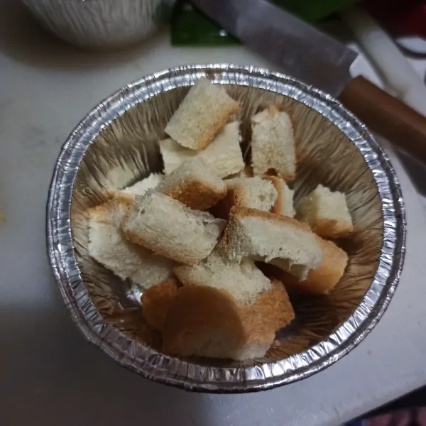 Potong pinggiran roti tawar kecil. Lalu letakkan di cup tahan panas atau daun pisang jika ada.