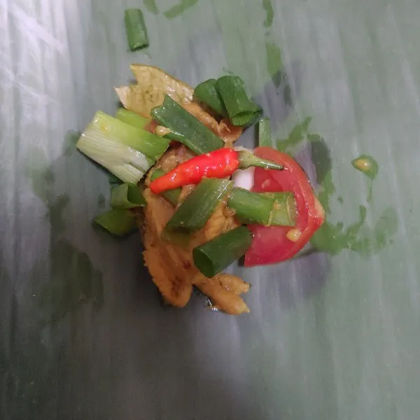 Siapkan daun pisang tambahkan daging ayam, beri daun bawang, tomat dan cabe rawit utuh. Lalu bungkus pincuk dan beri tusuk gigi.