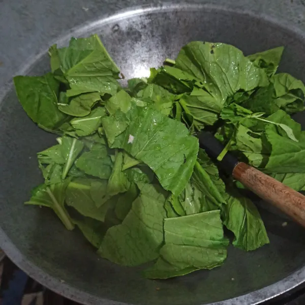 Masukkan daun caisim, beri sedikit air.