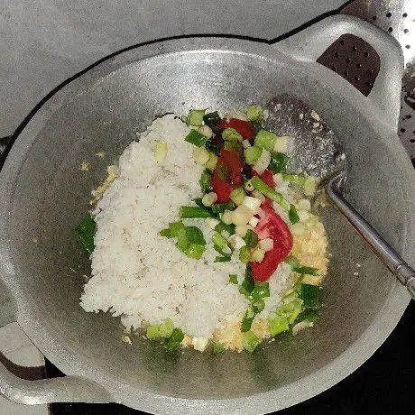 Masukkan nasi, irisan bawang prei, irisan tomat. Lalu bumbui dengan kaldu bubuk dan garam. Aduk rata, masak sampai aromanya wangi dan rasa sesuai selera