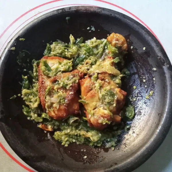 Letakkan ayam goreng kemudian penyetkan di atas sambal hijau. Sajikan bersama nasi hangat beserta lalapan.