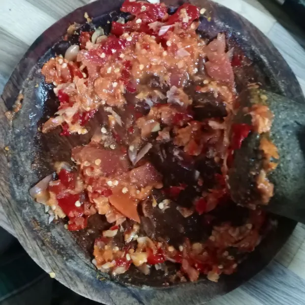 Haluskan bawang putih, bawang merah, cabe rawit, cabe merah keriting dan tomat merah.