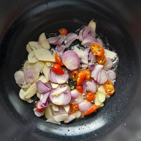 Panaskan secukupnya minyak goreng dalam wajan. Masukkan irisan bawang merah, bawang putih dan cabai rawit merah. Tumis hingga harum dan layu.