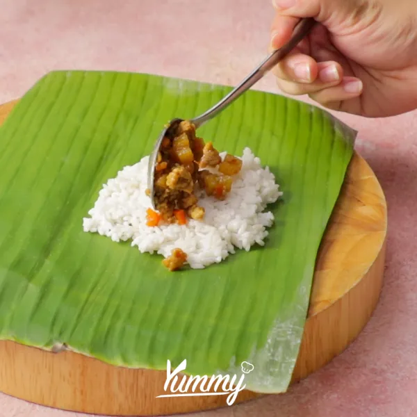 Dengan daun pisang berikan nasi dan pipihkan lalu berikan isian sebanyak 1 sendok makan lalu bungkus nasi.