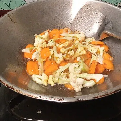Tuang secukupnya air, masukkan wortel dan bunga kol lalu aduk dan masak hingga setengah matang.