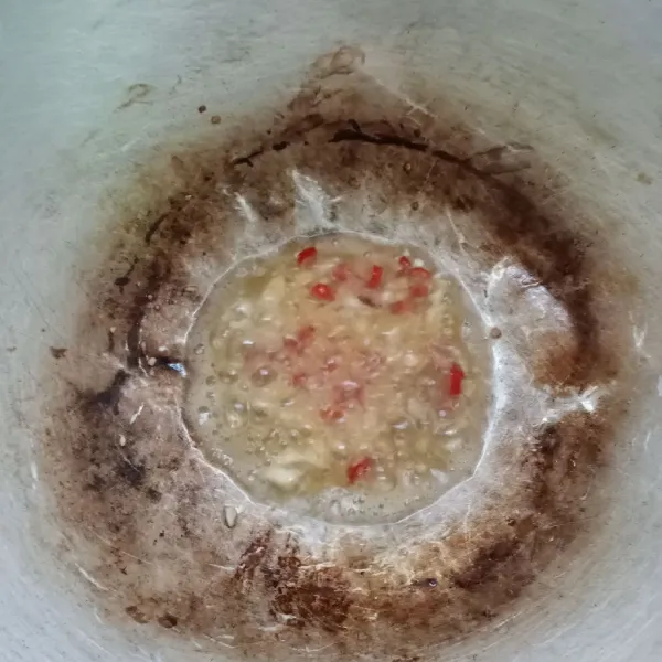 Tumis bawang putih dan cabe rawit sampai harum.