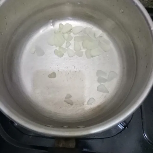 Siapkan air di panci lalu masukkan bawang putih iris.