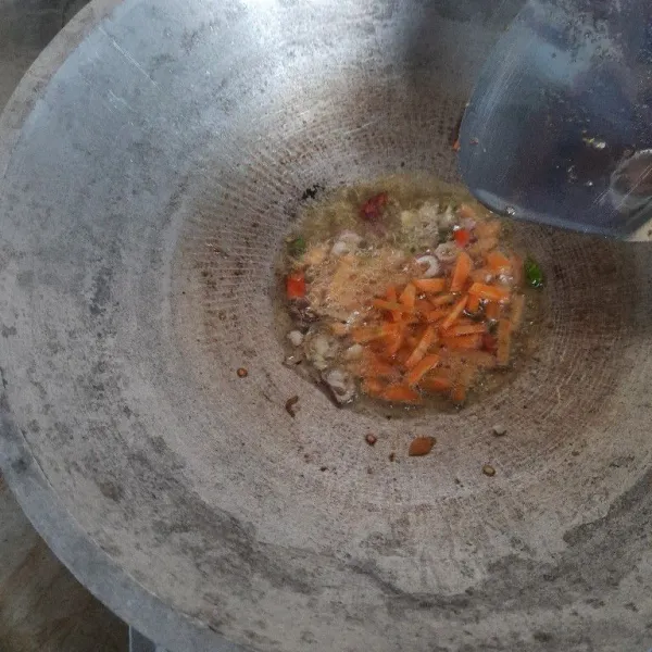 Selang 1 menit setelah tumisan bawang menguning kemudian masukkan irisan wortel tumis sebentar.