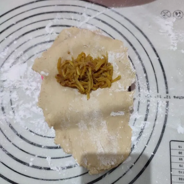 Letakkan adonan kulit di atas cetakan pastel, lalu isi dengan bahan isian..