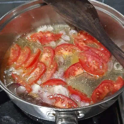 Panaskan minyak, tumis bawang merah hingga layu lalu masukkan potongan tomat dan masak hingga layu.