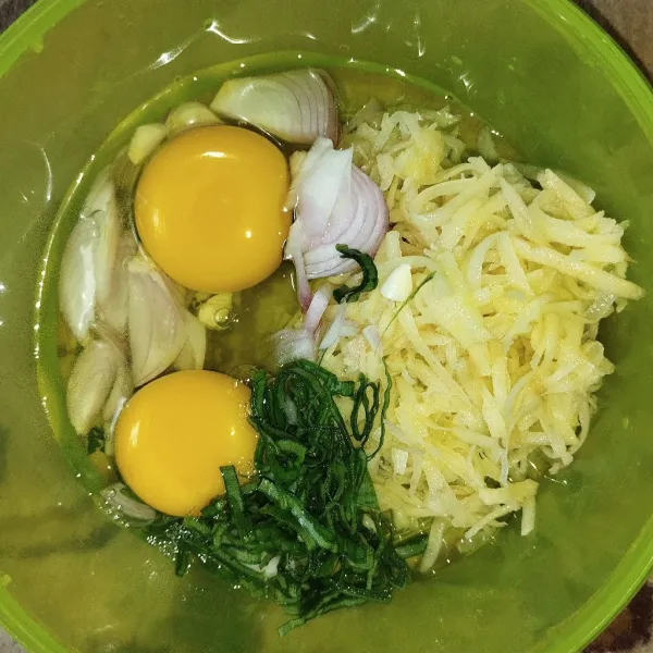 Dalam wadah campurkan kentang, bawang merah, bawang putih, daun kunyit, dan telur.
