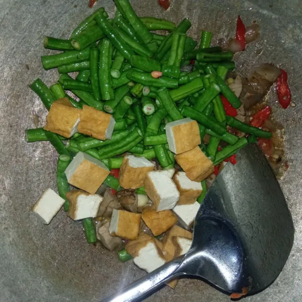 Tambahkan tahu dan kacang panjang lalu aduk hingga kacang panjang sedikit layu.