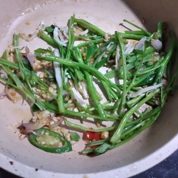 Masukkan bagian batang kangkung, lalu tambahkan ikan teri, aduk dan tumis batang kangkung hingga mulai layu.