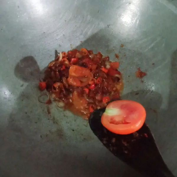 Haluskan bumbu kemudian tumis bersama irisan bawang merah hingga harum. Masukkan tomat dan irisan cabai rawit.