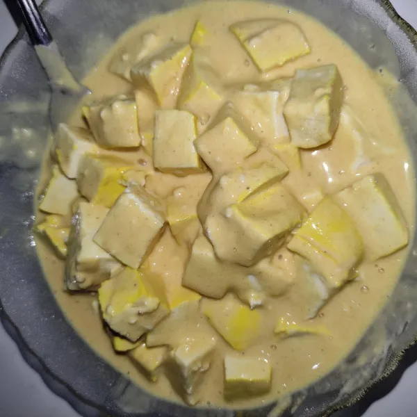 Masukkan potongan tahu, lalu baluri.