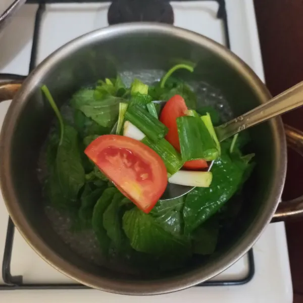 Tambahkan irisan daun bawang dan tomat merah, masak hingga matang.